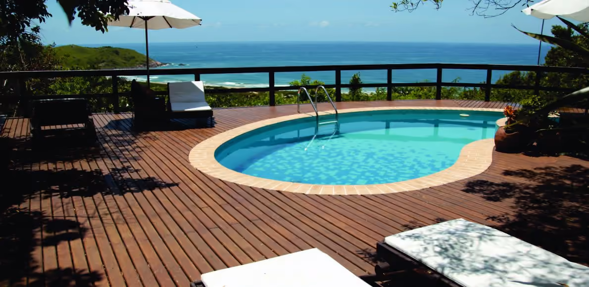 Piscina em deck de madeira da Bangalore Suites, no alto do morro da Praia do Silveira, com vista para o mar