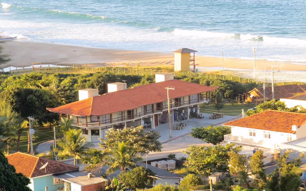 Prédio de telhado de cerâmica do Gamboa Luna y Sol Apart-Hotel, visto do alto, de frente para a areia e o mar da Praia da Gamboa