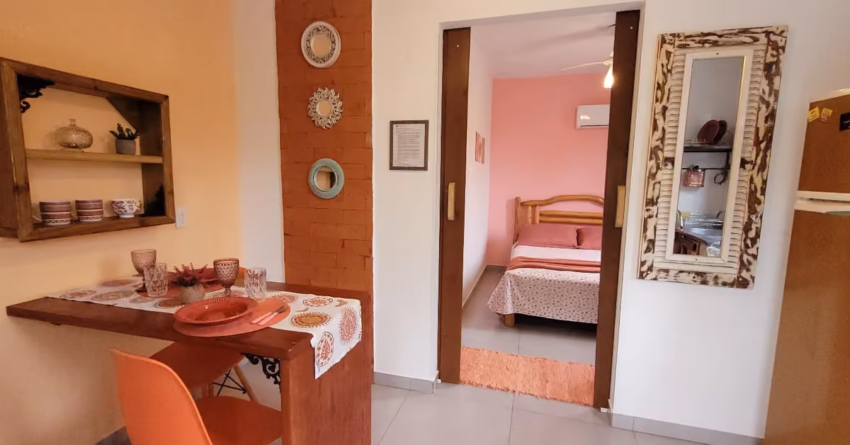 Apartamento da Morada das Orquídeas, na Guarda do Embaú, com mesa, cozinha e o quarto ao fundo
