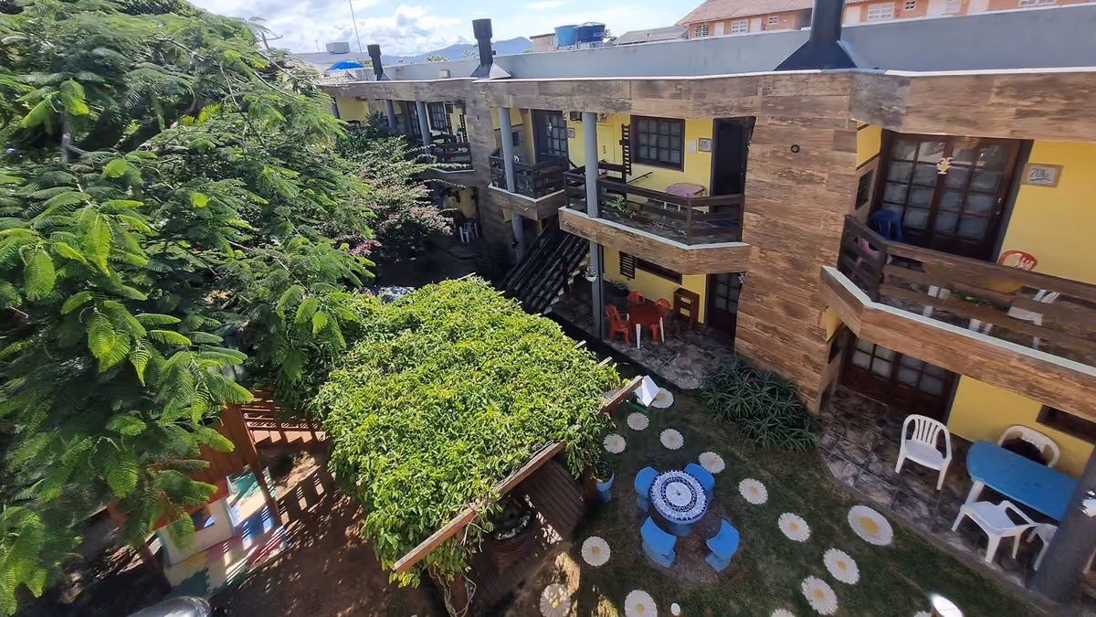 Pátio interno da Pousada Vila da Praia, na Praia de Cima, com jardim e os blocos amarelos em volta