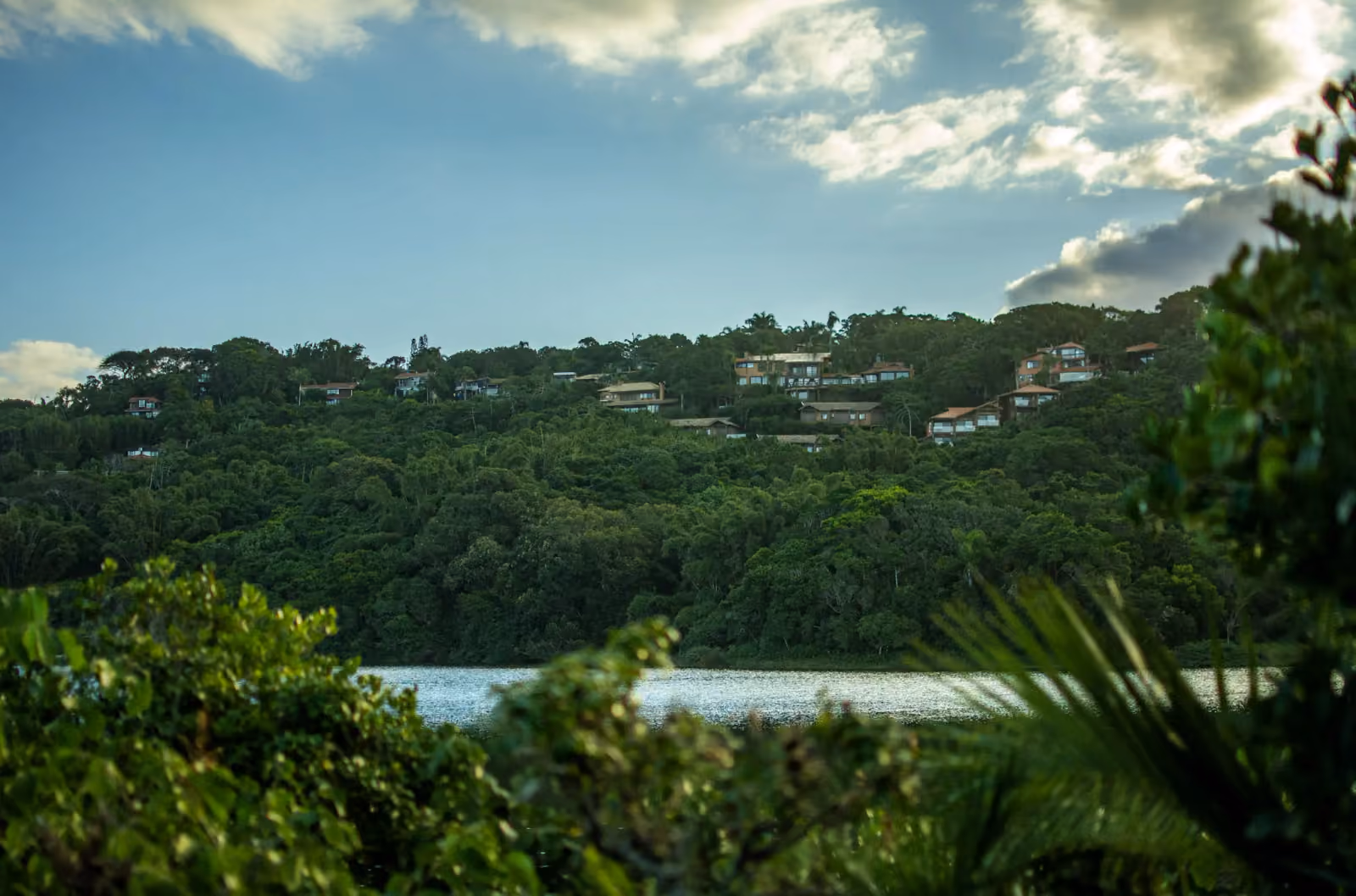 Lagoa do Meio, na Praia do Rosa, com casas espalhadas no morro coberto de mata