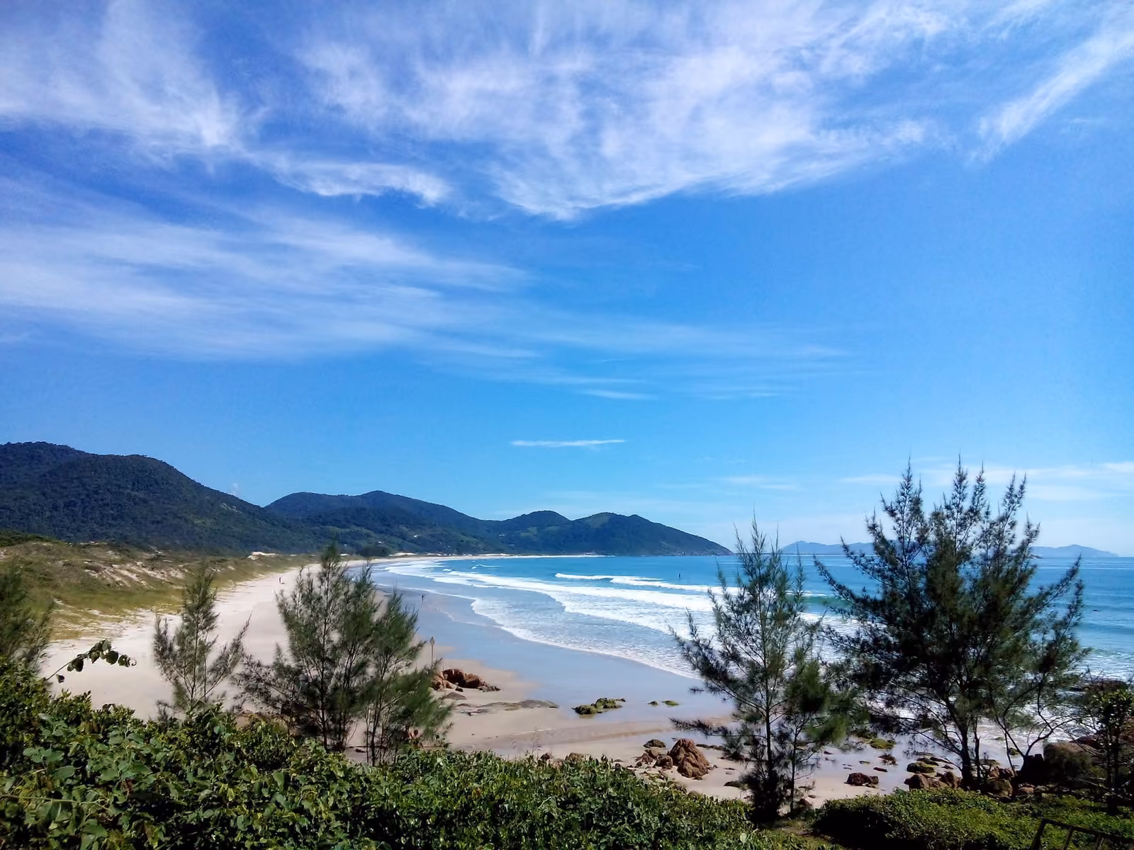 Praia do Siriú vista desde lo alto, con la arena entre la vegetación y los morros al fondo